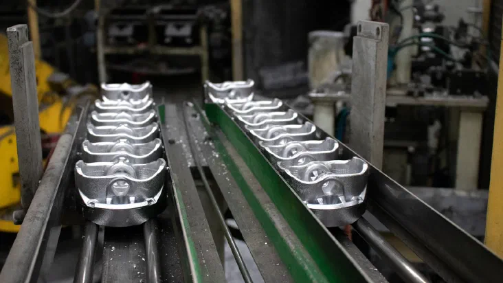 Metal components moving along an industrial conveyor belt on a factory assembly line