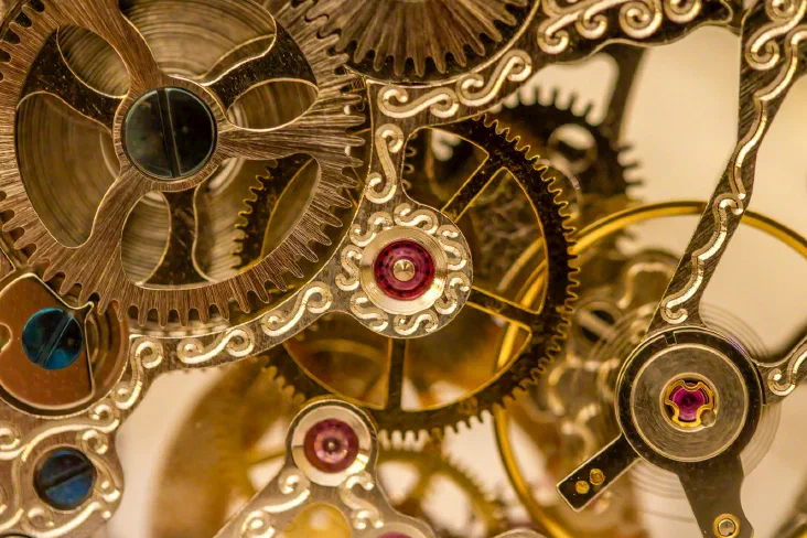 A close-up of a clock with its internal gears and mechanism exposed