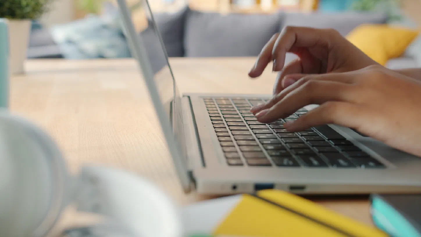 A pair of hands typing on a laptop keyboard at a desk