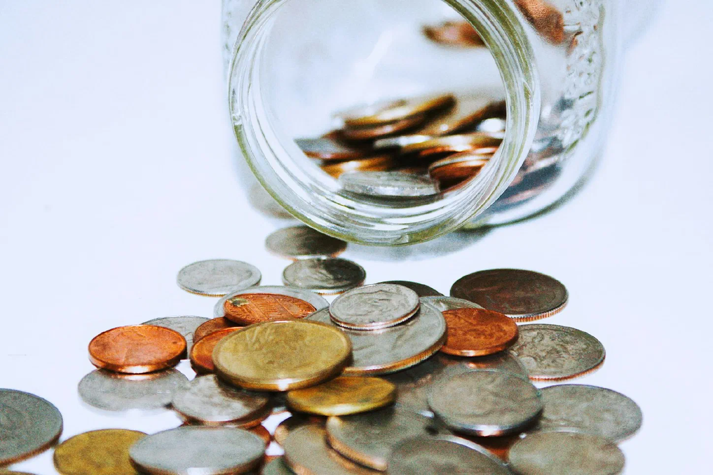 A clear glass jar filled with coins, illustrating savings